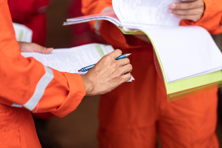 Close-up of two people writing notes in notepads.